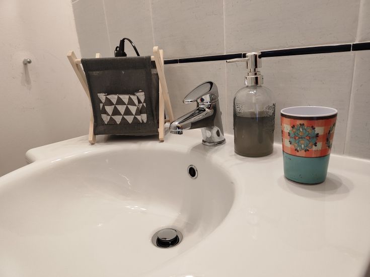 A simple sink with decorative accessories and a colorful cup, perfect for a contemporary bathroom.