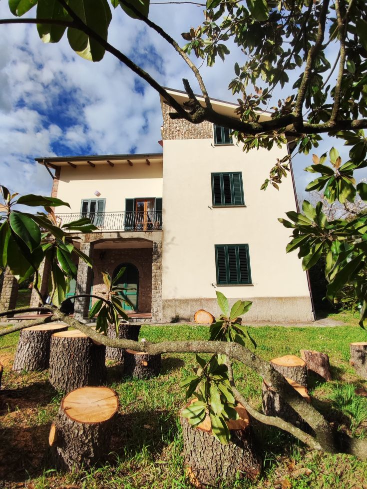 A villa surrounded by trees, with a clear sky and well-maintained green areas.