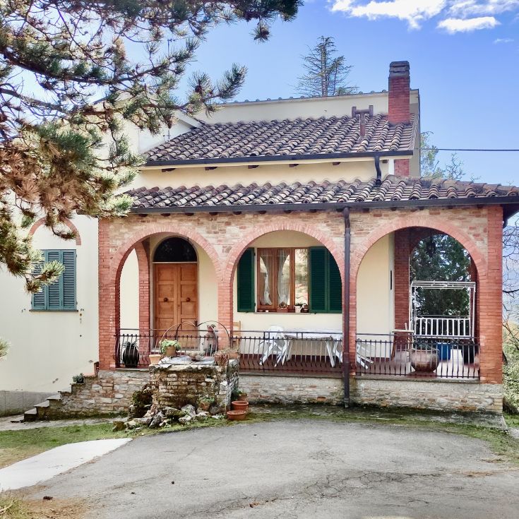 Building in a green area, featuring brick arches and a well-maintained porch.