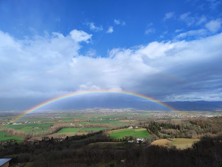 A colorful rainbow stretches across the hilly landscape on the horizon.