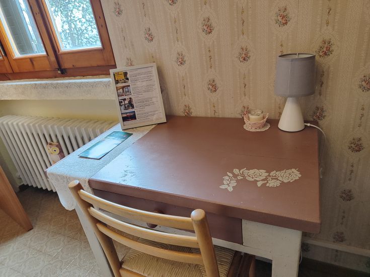 A simple workspace featuring a wooden table, a desk lamp, and some floral decorations.