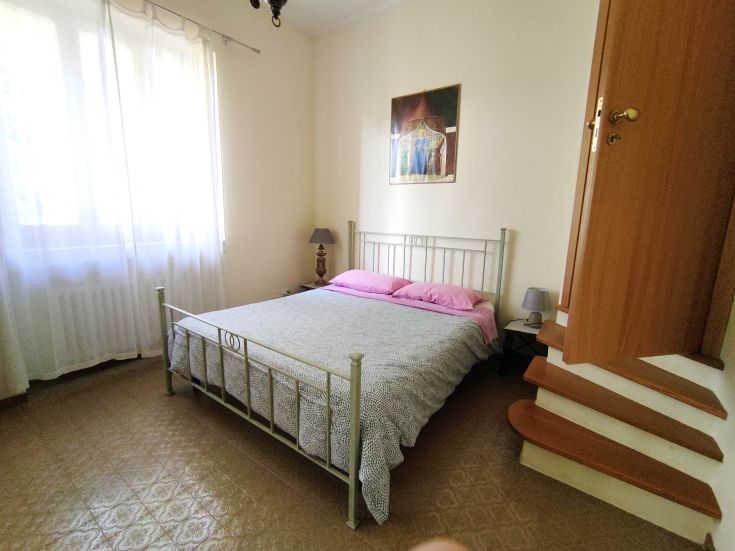 Simple bedroom featuring a double bed, illuminated by natural light coming through the window.