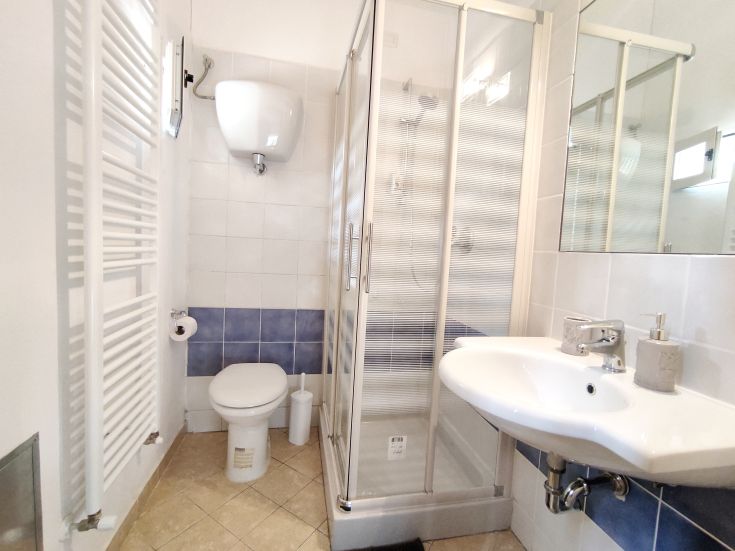 A modern bathroom featuring a shower, sink, and sanitary fixtures, finished with light and simple tiles.