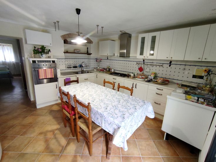 Spacious kitchen with a set dining table and light-colored furniture, perfect for sociable lunches.