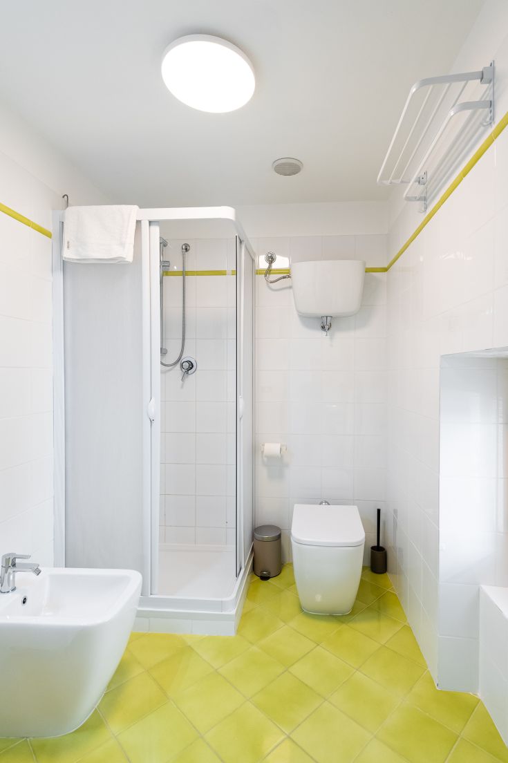 Modernes Bad mit Dusche und gelbem Boden. Sauberer und gut beleuchteter Raum.