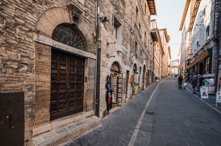 Eine historische Straße im Stadtzentrum, umgeben von Steinbauten und Geschäften.