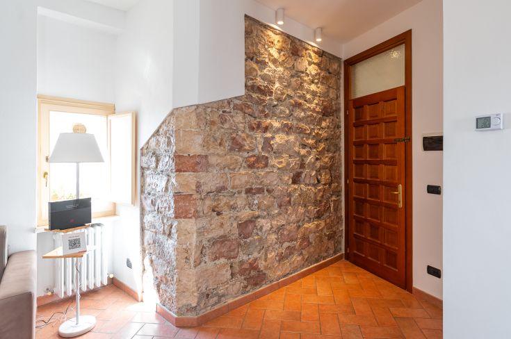 Eingang einer Wohnung mit hellen Steinwänden und einer einfachen Holztür.