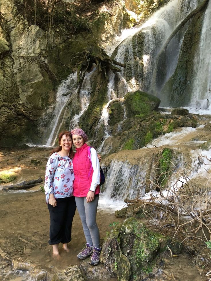 Due amiche si rilassano in un'atmosfera tranquilla vicino a una cascata, circondate dalla natura.