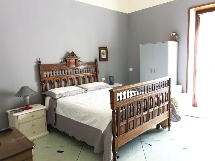 Camera matrimoniale spaziosa con letto in legno, arredamenti classici e tocchi di modernità.