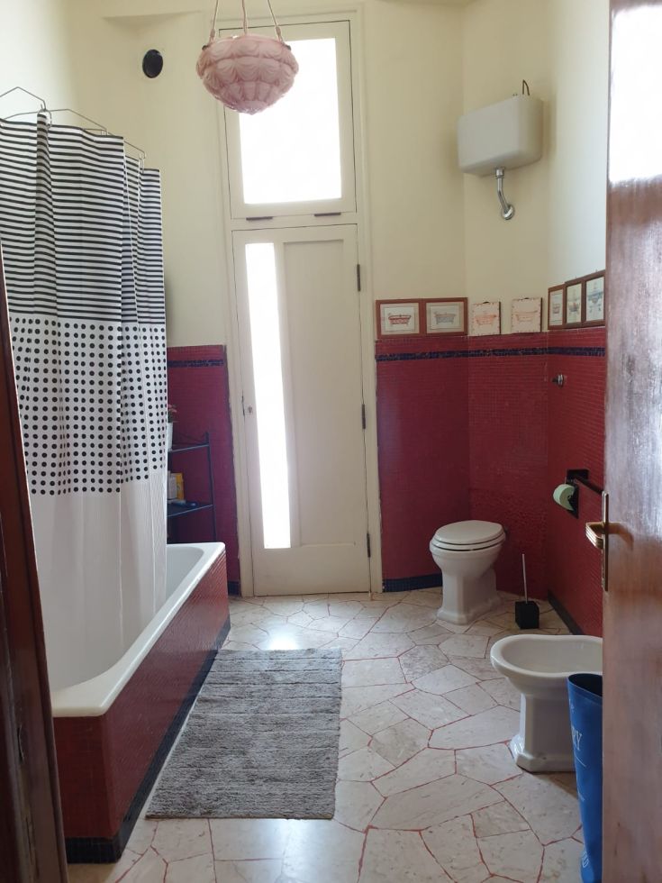 Bagno caratterizzato da piastrelle rosse e decorazioni sobrie, offre un'atmosfera accogliente e luminosa.