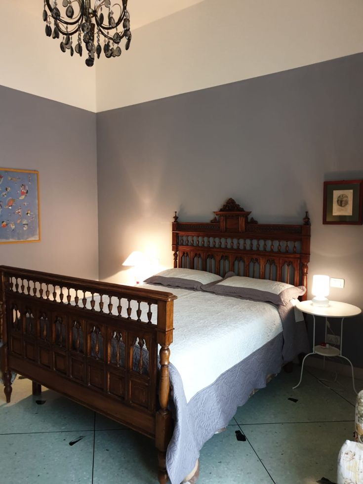 Ambiente accogliente e sobrio, con un letto in legno e elementi decorativi discreti.