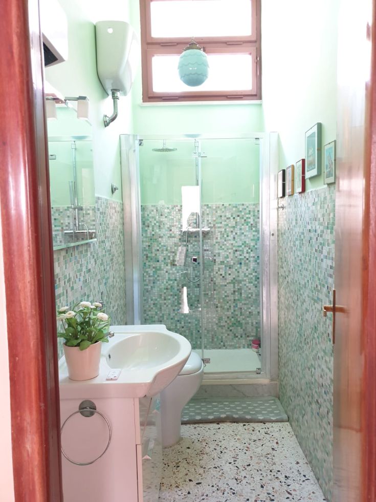Bagno spazioso e ben illuminato con piastrelle dai colori vivaci e una doccia. Ambiente rilassante e funzionale.