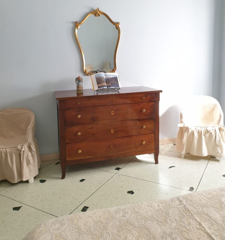 Camera semplice con comò in legno e uno specchio. Gli arredi creano un'atmosfera confortevole.