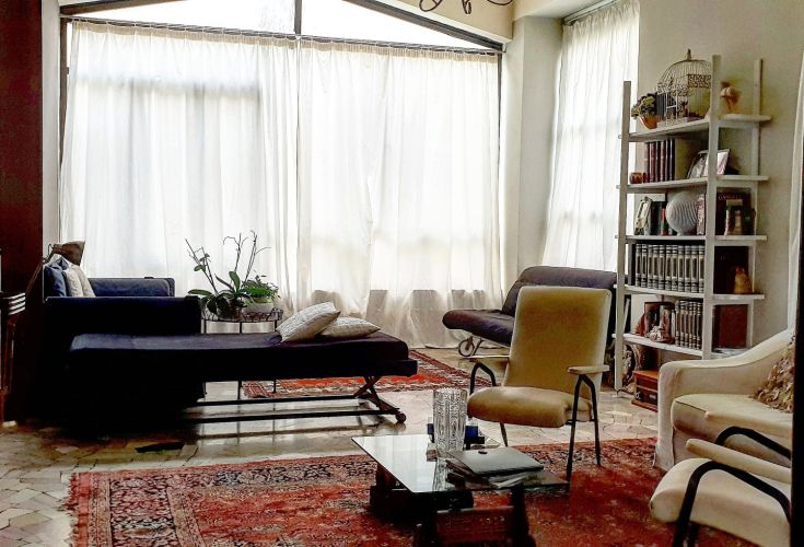 Un soggiorno spazioso e ben illuminato, arredato con tende chiare e mobili semplici.