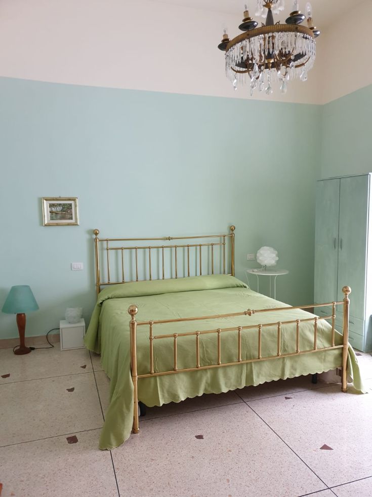 Ambiente tranquillo e luminoso con un letto in legno e elementi d'arredo semplici.