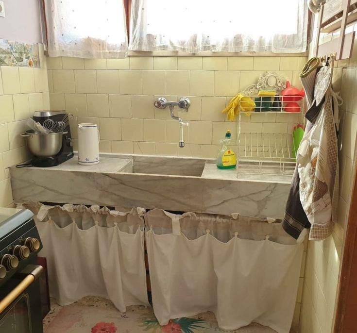 Cucina semplice e funzionale, dotata di un lavello in marmo e elementi pratici per un uso quotidiano.