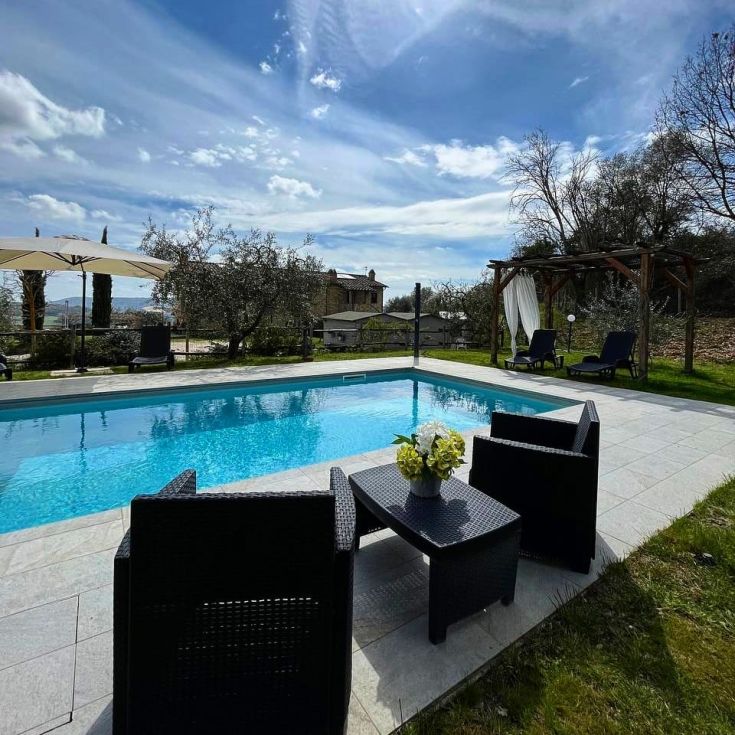 Une piscine nichée dans la verdure, entourée d'oliviers et offrant une belle vue sur la campagne.