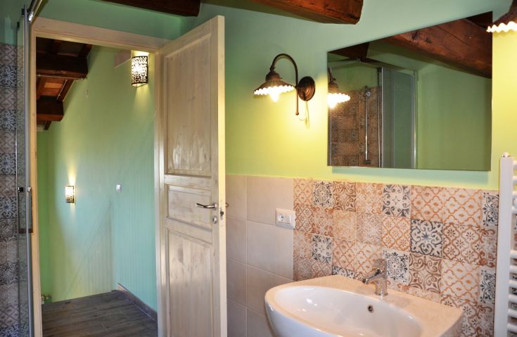 Bagno modernizzato con pavimento fine e box doccia, che appare spazioso e ben illuminato.