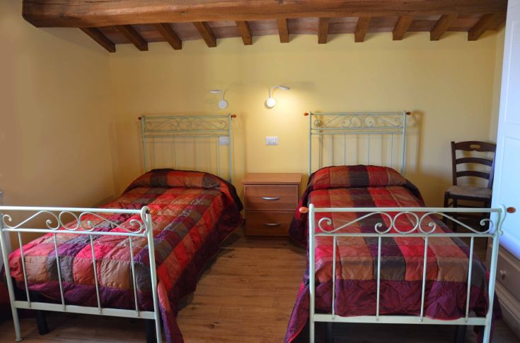 Camera con letti singoli, decorazioni semplici e ambiente confortevole in agriturismo.