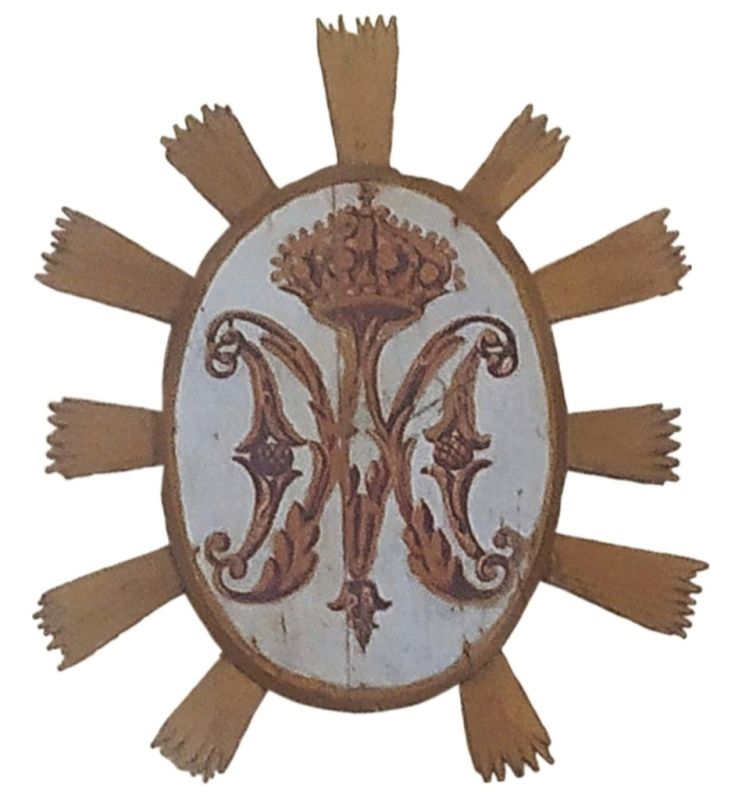 Decorative coat of arms featuring crown elements and initials, referencing historical traditions.