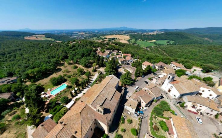 Scene of a peaceful village surrounded by trees and greenery, with simple houses lined along a road.