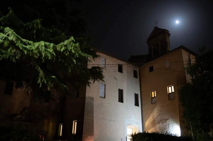 An ancient monastery illuminated by moonlight, surrounded by lush nature in a serene atmosphere.