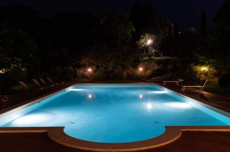A lit pool in a green setting, creating a serene atmosphere at night.