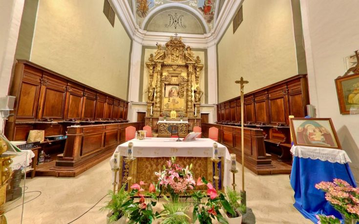 The interior of a historical monastery, featuring a simple altar and decorations reflecting the era's style.