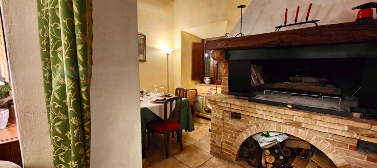Cozy corner with a rustic fireplace, table for intimate dinners, and warm atmosphere.