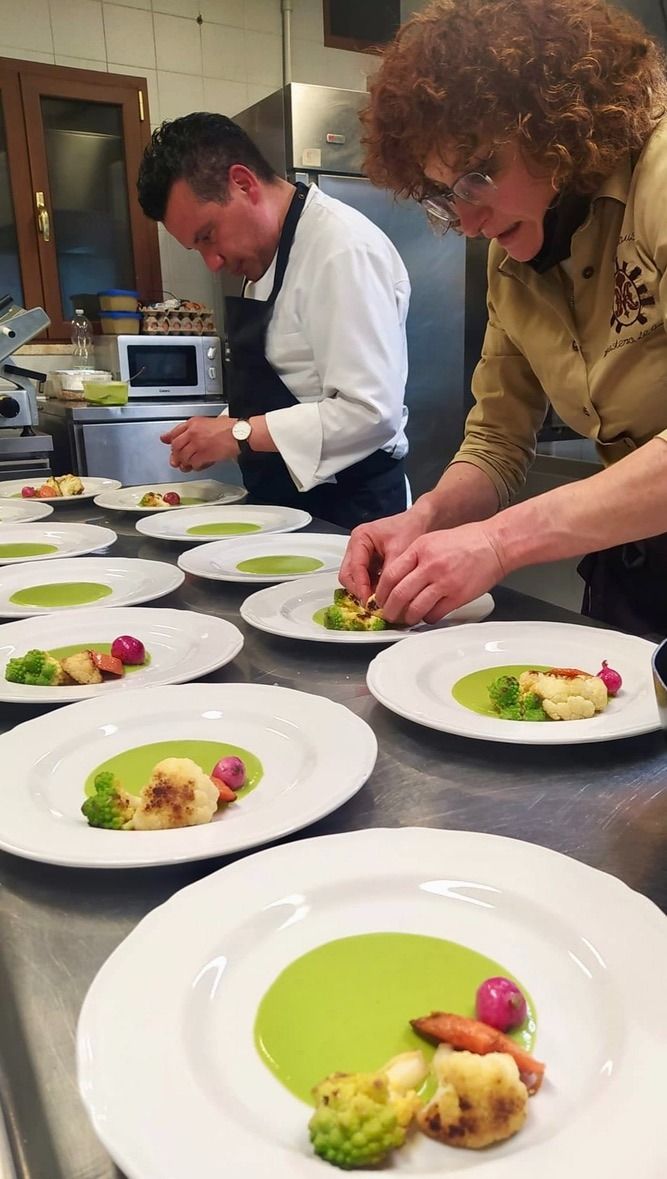Two chefs prepare dishes in a professional kitchen, surrounded by tools and ingredients.