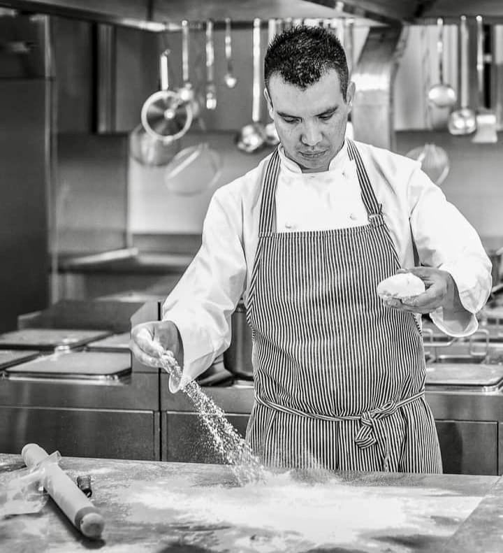 A chef sprinkles flour while creating new dishes in a restaurant kitchen.
