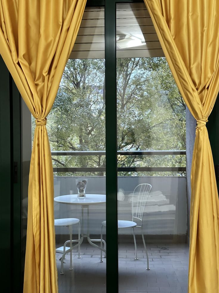 Outdoor space featuring a large balcony furnished with a table and chairs, surrounded by nature.