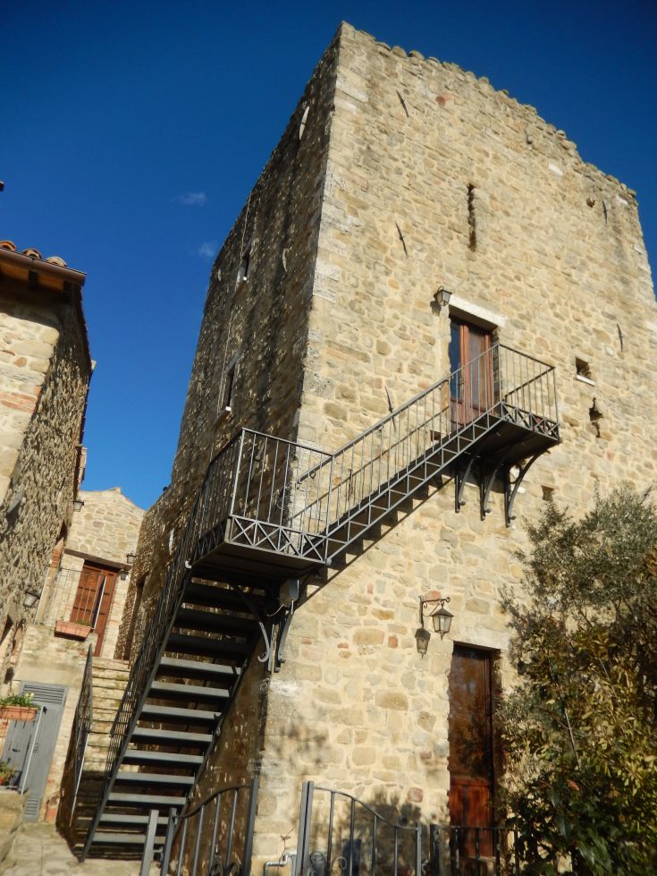 Ein Steinturm mit Außentreppen, unter einem klaren Himmel.