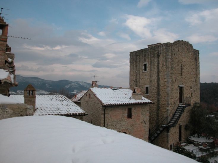 Ein historisches Gebäude, bedeckt mit Schnee, mit einem Steinturm unter einem bewölkten Himmel.