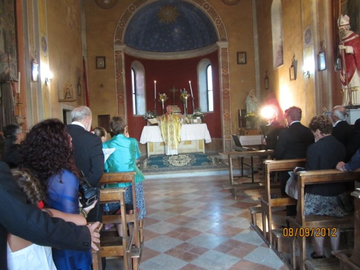 Religiöse Zeremonie in einer vollen Kirche, mit einem Priester am Altar und mehreren Gläubigen anwesend.
