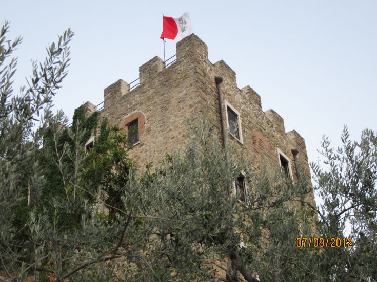 Ein Steingebäude mit einer Flagge, umgeben von Bäumen. Ländliche Umgebung in Umbrien.