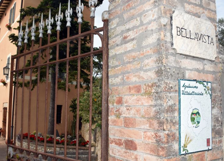 Zugang zum Agriturismo Bellavista, mit einem einfachen Zaun und einem gepflegten Garten mit Blumen.