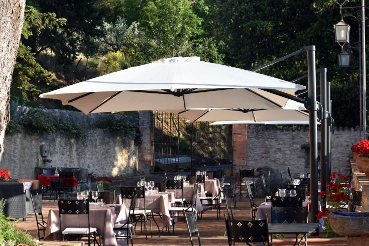 Aussicht auf eine Außenterrasse mit Tischen und Sonnenschirmen, umgeben von üppigem Grün.