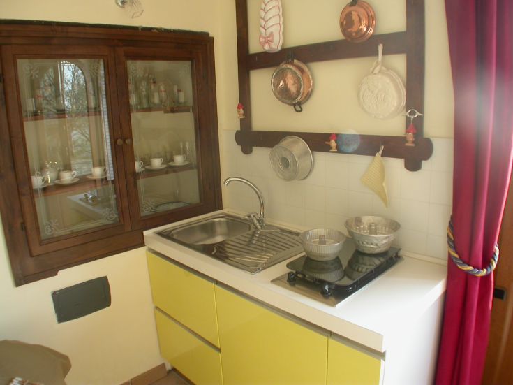 Cucina calda e accogliente con mobili gialli e elementi di design rustico, ideale per socializzare.