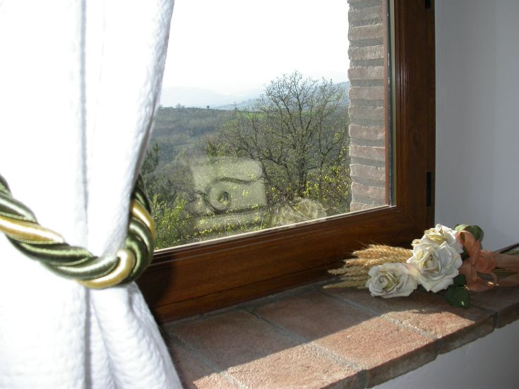 Panorama da una finestra di un semplice appartamento situato su una collina verde.