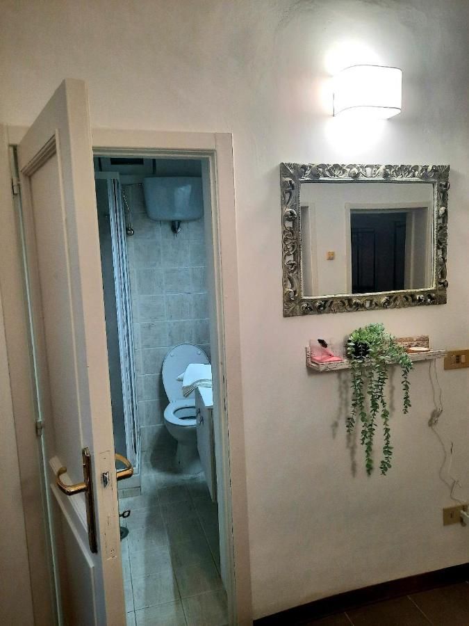 Entrée d'un appartement avec une salle de bain visible. La décoration est moderne et sobre, avec un miroir au mur.