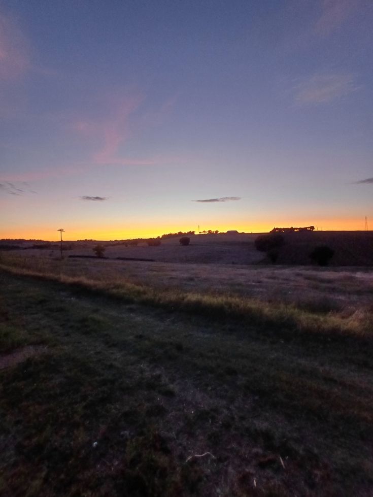 Un tramonto calmo su dolci colline, con un cielo sereno che sfuma nei colori del crepuscolo.