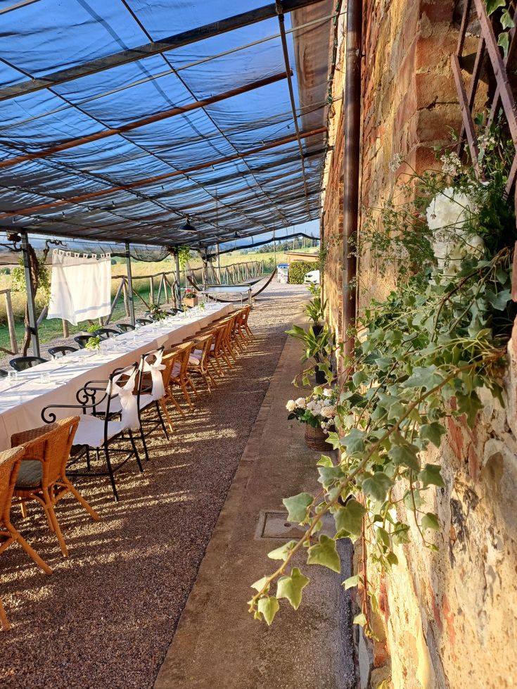 Un tavolo lungo all'aperto, circondato da alberi e natura, allestito per un evento tra le colline.
