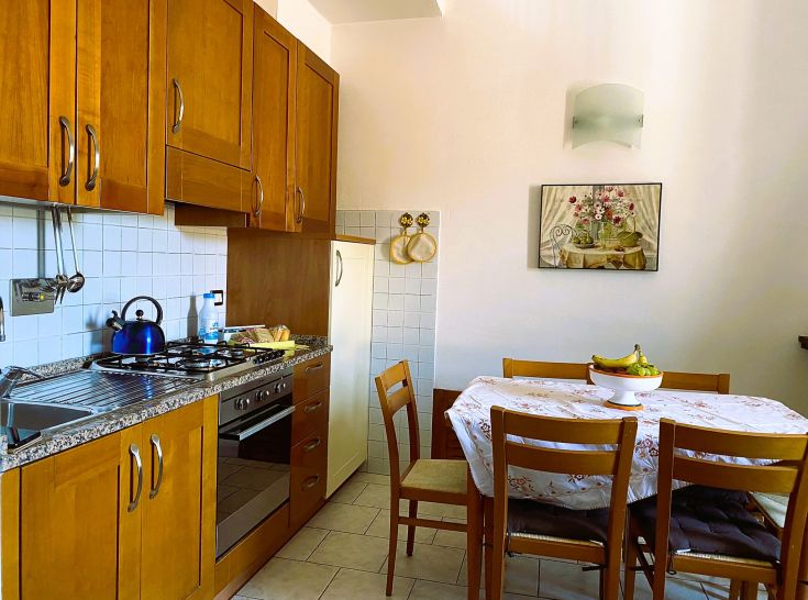Spacious and well-lit kitchen with light wood furniture and a nicely set table.