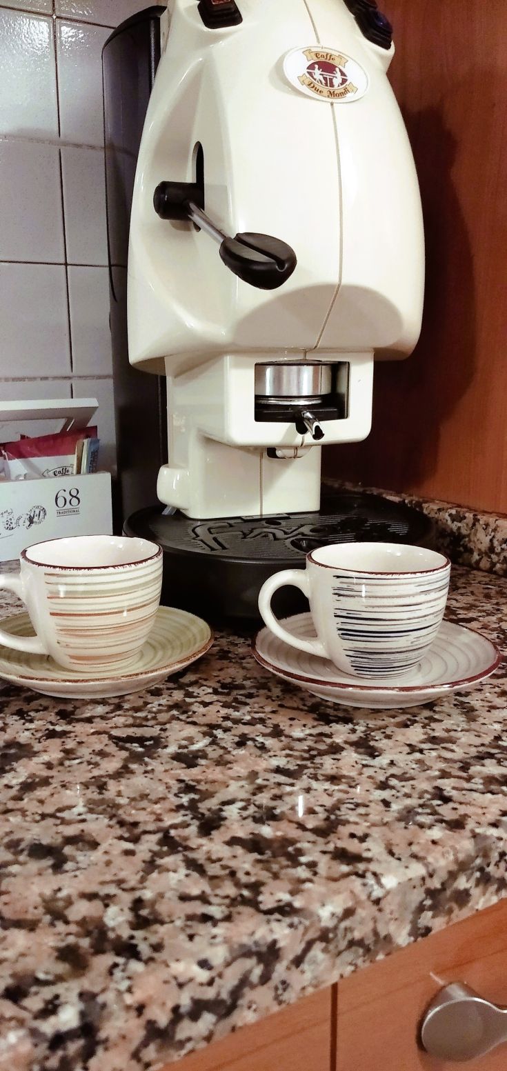 Coffee machine and cups arranged on a table in a cozy, inviting kitchen for a break.
