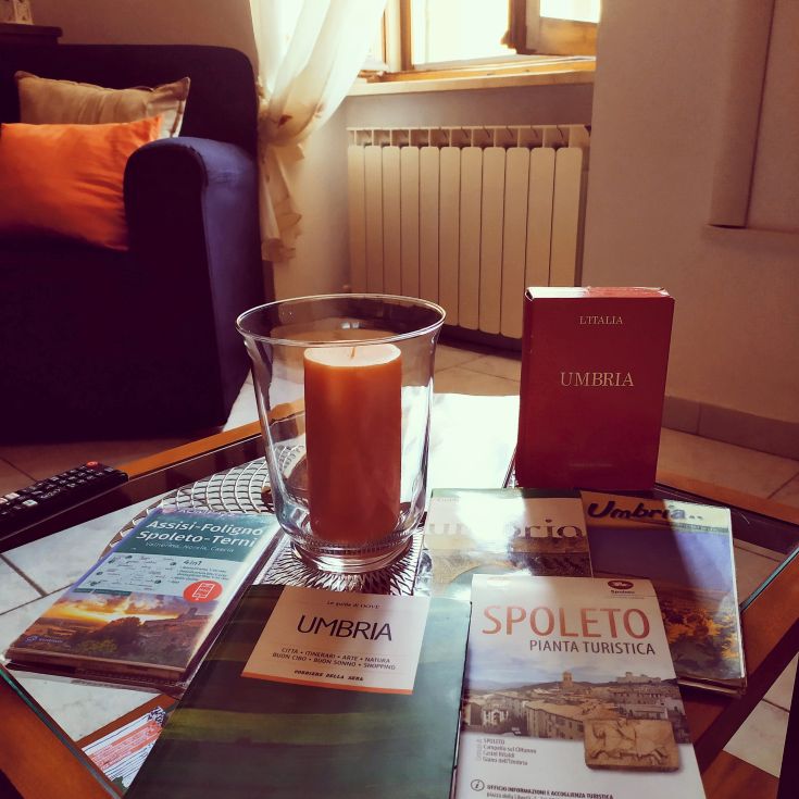 A cozy corner with candles and tourist brochures, perfect for exploring the Spoleto area.