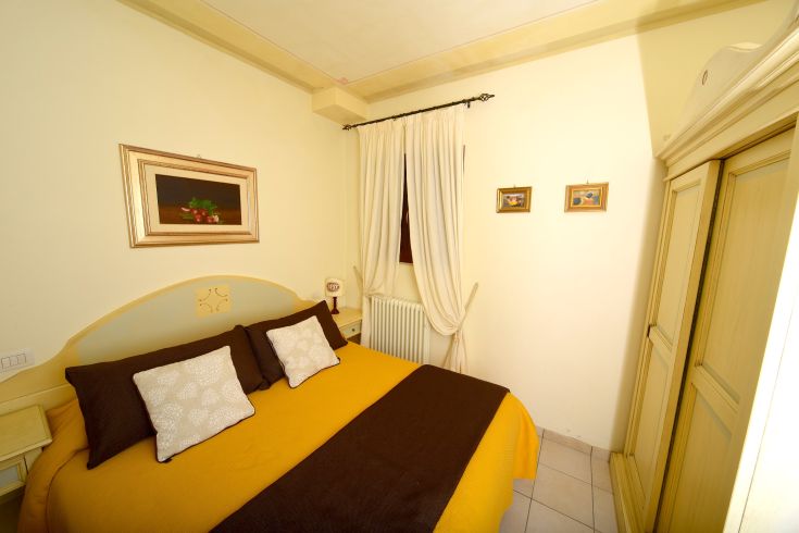 A simple designed bedroom featuring a double bed, light decorations, and good natural lighting.