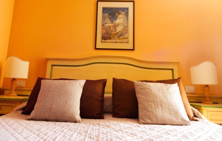 Simple room with orange walls, a comfortable bed, and decorative elements on the walls.