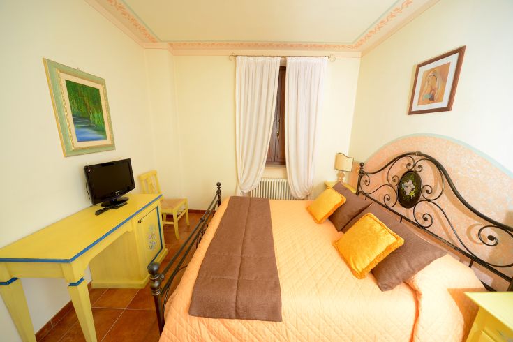 Cozy room with a double bed and vibrant decor, warmly illuminated by sunlight.