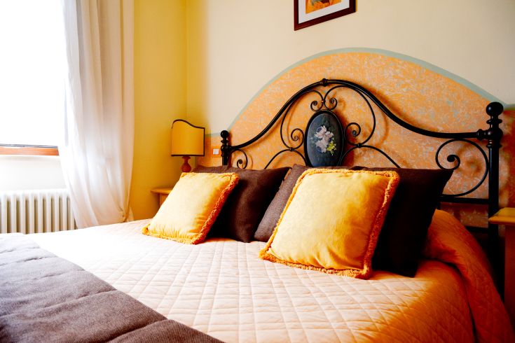 Simple room with a double bed and decorative pillows in the Luncinaia Residence.